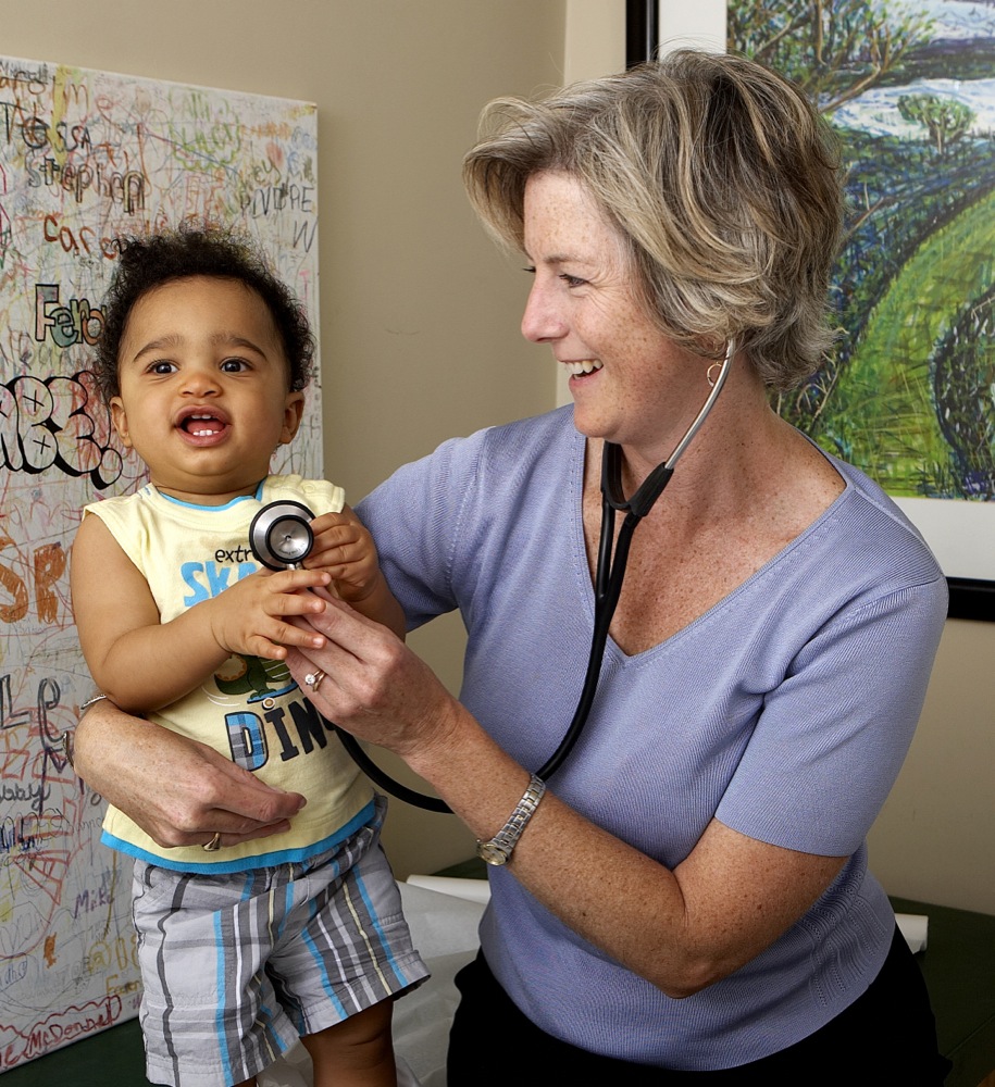 Woman using stethoscope on child